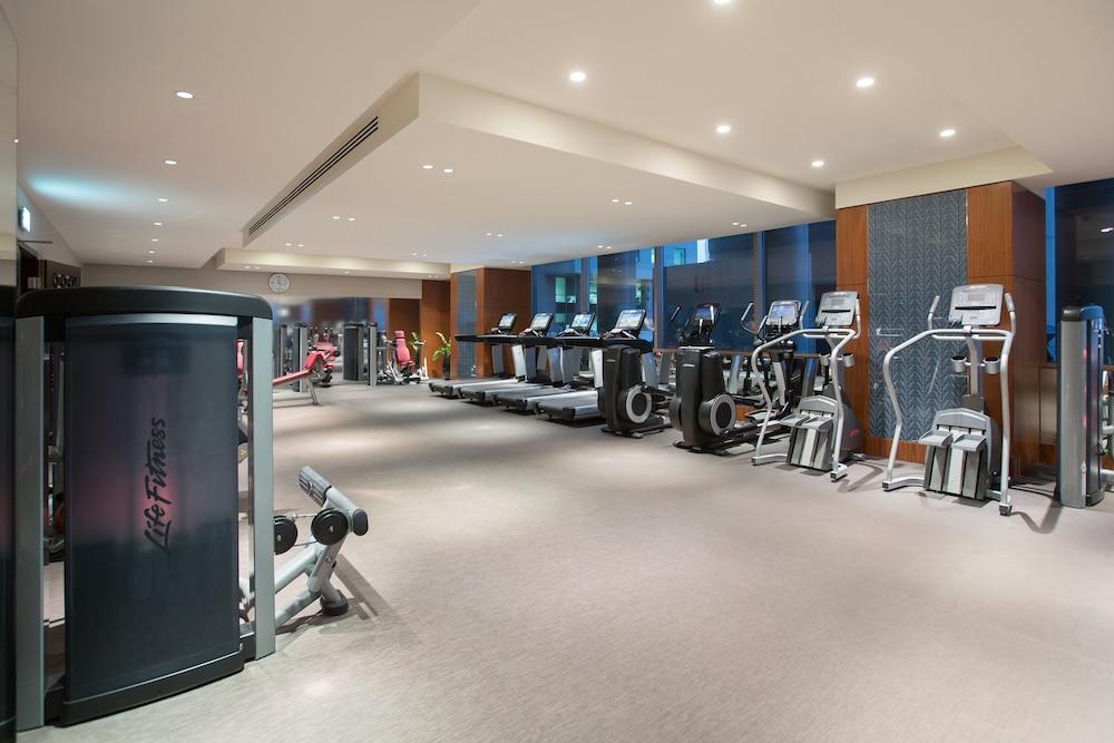 Millennium Plaza Doha Hotel Exterior photo The photo shows a modern gym interior. It features various exercise machines, including treadmills, elliptical machines, and weight equipment. The space is well-lit with overhead lights, and there are large windows allowing natural light to enter. Th