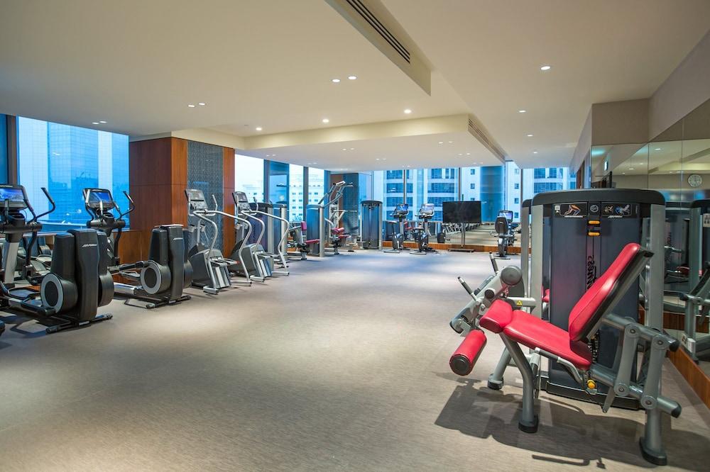 Millennium Plaza Doha Hotel Exterior photo The photo shows a modern gym or fitness center. It features various exercise equipment, including cardio machines like treadmills and stationary bikes, along with strength training machines. The space is well-lit with large windows providing natural 